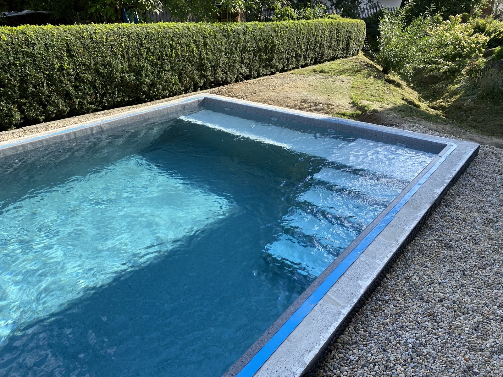 Gartenpool mit Römertreppe und klarem blauem Wasser